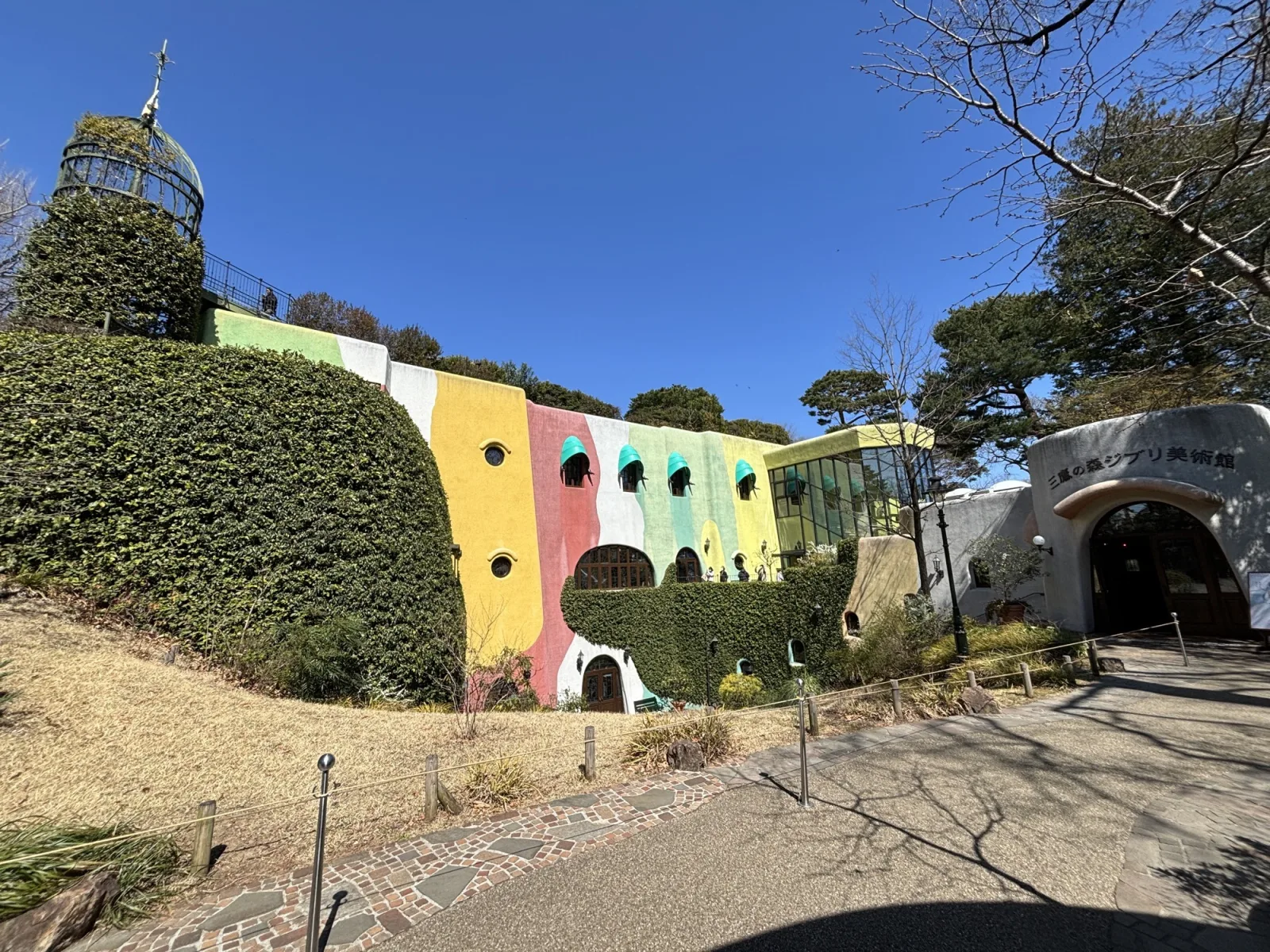 The colourful ivy covered facade and arched entrance of the Ghibli Museum in Mitaka under a blue sky