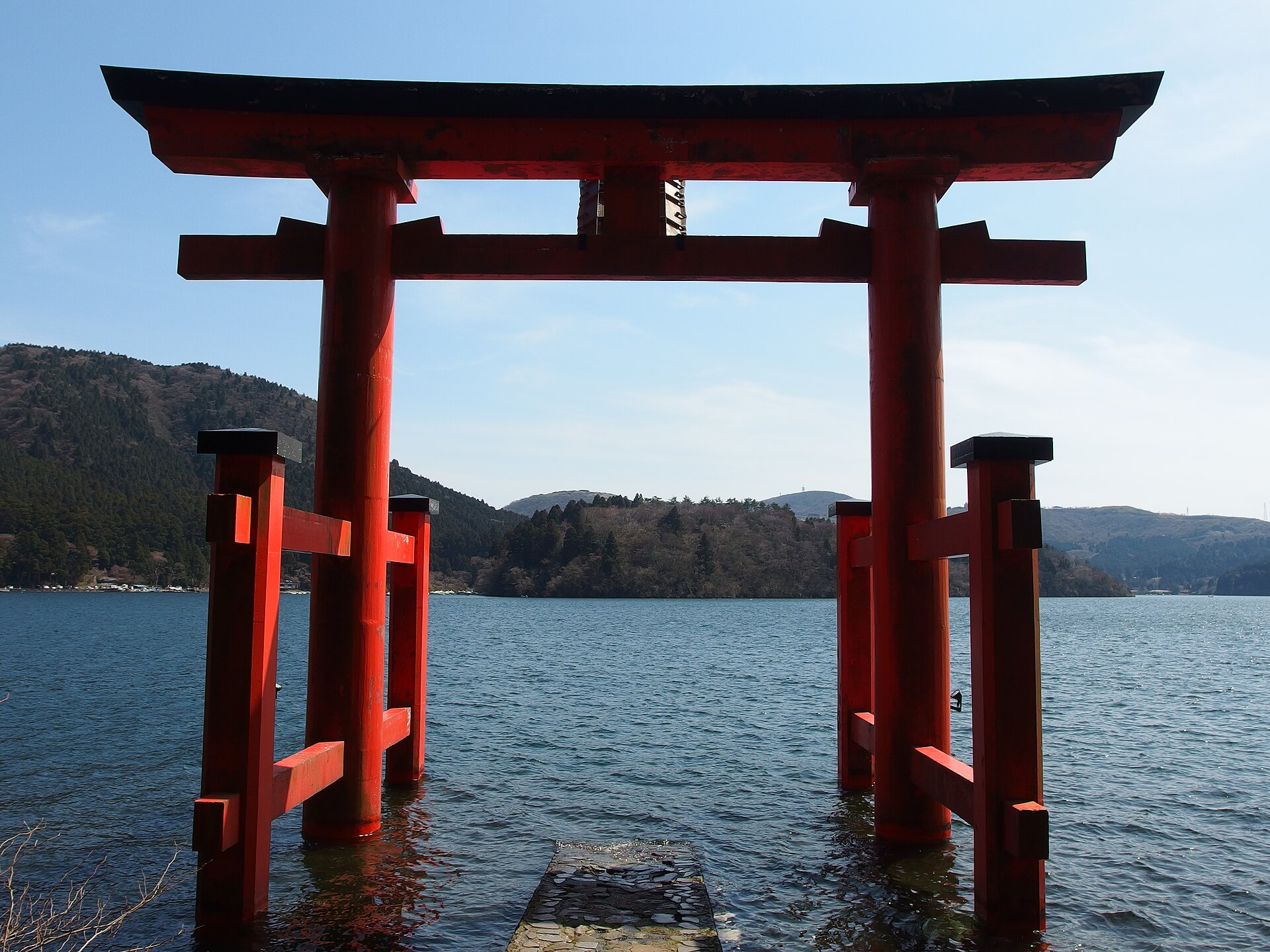 El torii rojo sobre el Lago Ashi en Hakone con las colinas detrás