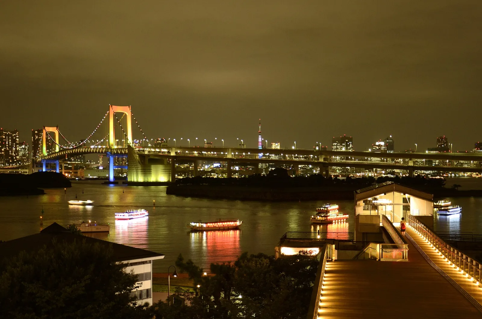 The Rainbow Bridge, Tokyo Tower and the city lights on the water, seen from the Odaiba waterfront at night
