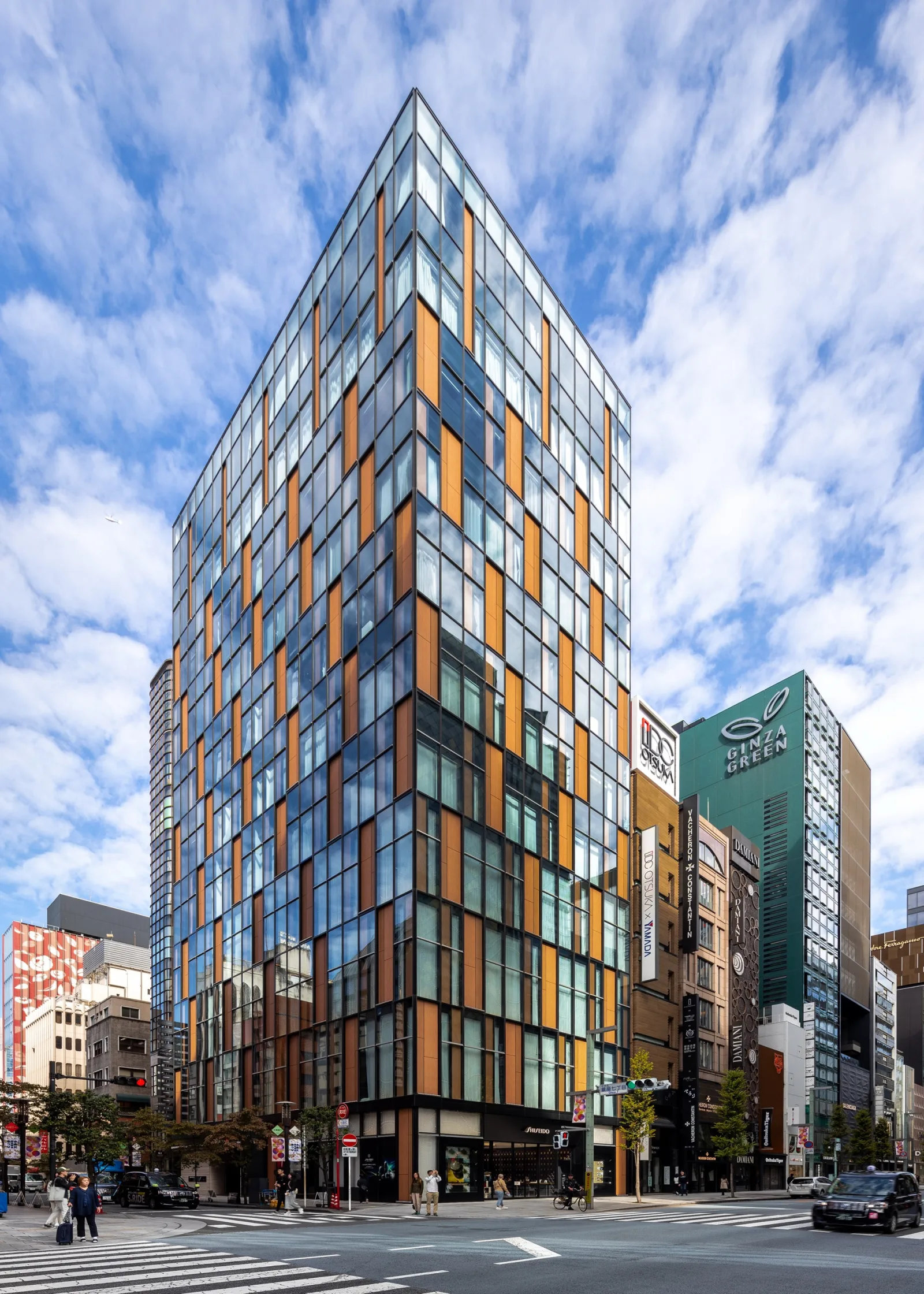 The glass and copper tower of SHISEIDO THE STORE on a Ginza street corner under a blue sky